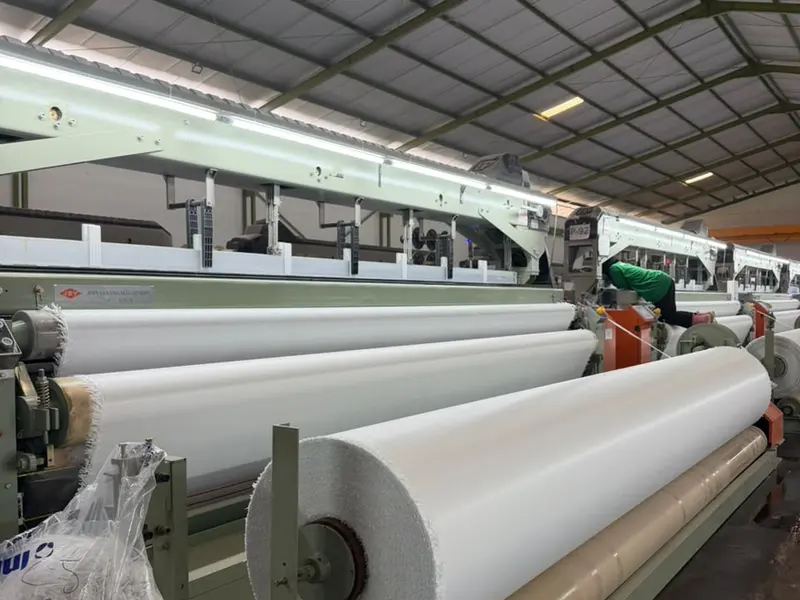 Rol kain putih besar keluar dari mesin tenun industri Yo Tarpaulin